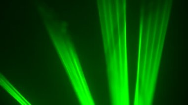 Siyah dumanlı arka planda konser sırasında parlak yeşil neon ışıklar yanıp sönüyor. Lazer ışıkları dumanla hareket eder. Profesyonel renkli ışıklandırma ve parti için ışık gösterisi efektleri. Kapat..