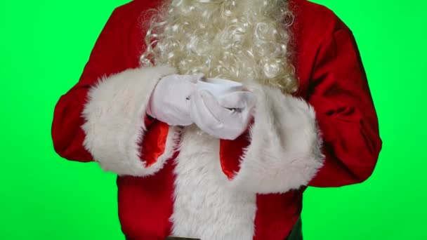 Beyaz eldivenli ve kırmızı elbiseli Noel Baba ellerini fincanda ısıtıyor ve sıcak çaydan hoşlanıyor. Stüdyoda yeşil bir ekranda izole edilmiş. Krom anahtar. Kapatın. Yavaş çekim. — Stok video
