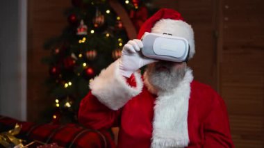 Sanal gerçeklik gözlüğü takan Noel Baba 'nın portresi. Yüzünde şaşırmış bir ifade var. Yeni yılınız kutlu olsun. Yavaş çekim.