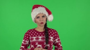 Noel Baba şapkalı tatlı kızın portresi dikkatle dinliyor ve seyirciyi işaret ediyor. Yeşil Ekran