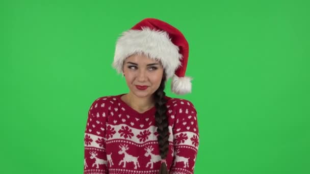 Ritratto di ragazza dolce in cappello di Babbo Natale è civettuolmente sorridente mentre guarda la fotocamera. Schermo verde — Video Stock