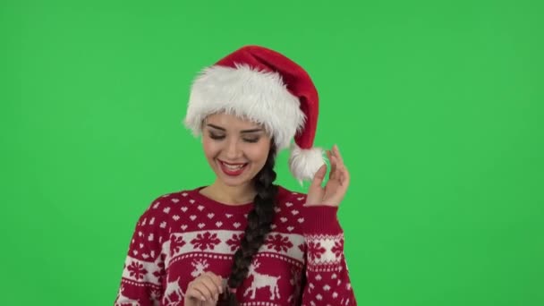 Портрет милой девушки в шляпе Санта-Клауса кокетливо улыбается, глядя в камеру. Зеленый экран — стоковое видео