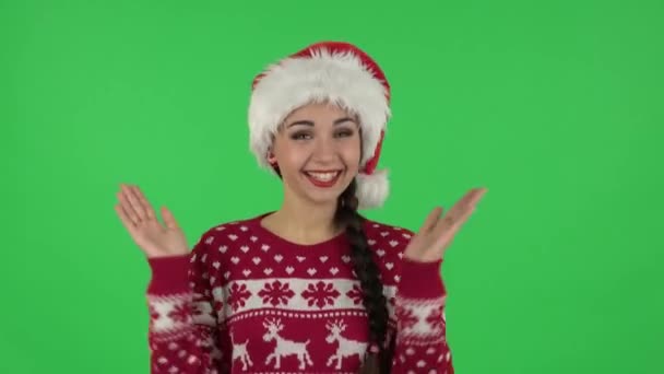 Portret słodkiej dziewczyny w kapeluszu Świętego Mikołaja klaska dłońmi z zachwytem i radością. Zielony ekran — Wideo stockowe
