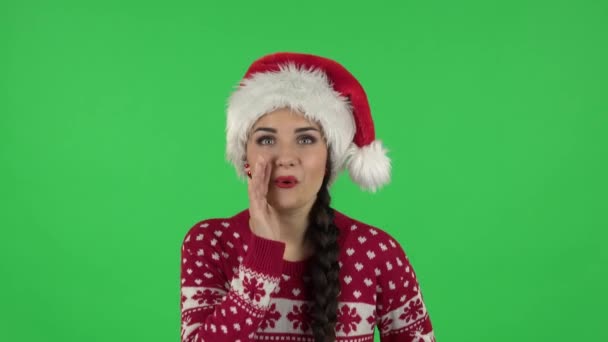 Ritratto di ragazza dolce in cappello di Babbo Natale si sta coprendo la bocca con la mano e sussurrando segreto. Schermo verde — Video Stock