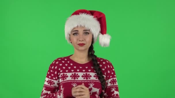 Portret van een lief meisje in de kerstman hoed is op zoek met tederheid met gevouwen armen voor haar. Groen scherm — Stockvideo