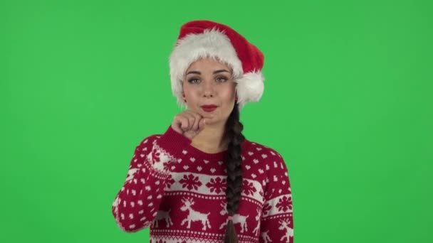 Portret słodkiej dziewczyny w kapeluszu Świętego Mikołaja uśmiecha się i pokazuje serce palcami, a następnie dmuchając pocałunek. Zielony ekran — Wideo stockowe