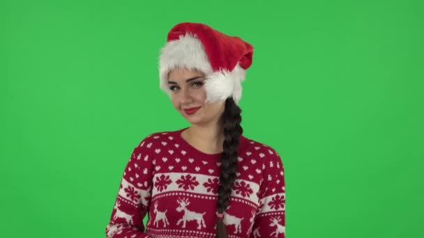 Porträtt söt flicka i jultomten hatt förföriskt leende och gest hotar genom att skaka pekfingret. Gråruta — Stockvideo