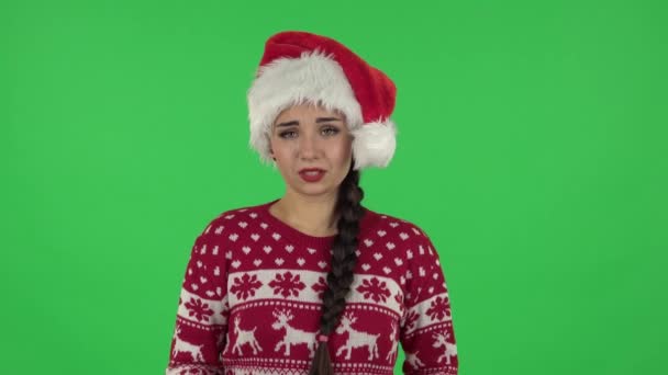 Портрет милой девушки в шляпе Санта-Клауса стоит беспокоясь в ожидании, а затем улыбается с облегчением. Зеленый экран — стоковое видео