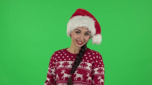 Porträtt av söt flicka i Santa Claus hatt talar och pekar sida hand för något, kopiera utrymme.. Grön skärm — Stockvideo