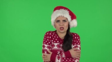 Noel Baba şapkalı tatlı kızın portresi dondu ve ısınmaya çalışıyor. Yeşil Ekran