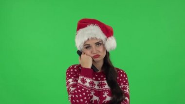 Noel Baba şapkalı tatlı kız portresi elinde uzaktan kumandayla TV 'yi açıyor. Yeşil Ekran