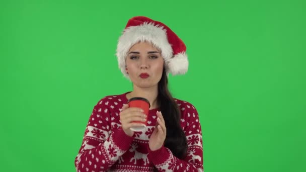 Портрет милой девушки в шляпе Санта Клауса пьет неприятный кофе. Зеленый экран — стоковое видео