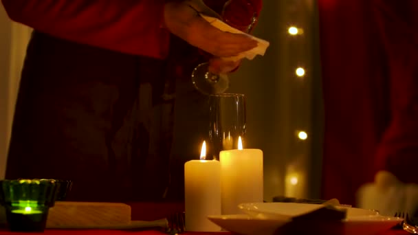 Kobieta organizuje talerze, wyciera kieliszki do szampana na tle pokoju urządzone z okazji Nowego Roku lub Bożego Narodzenia. Świece płonące na świątecznym stole. Mało światła. Ręce do góry. Zwolniony ruch. — Wideo stockowe