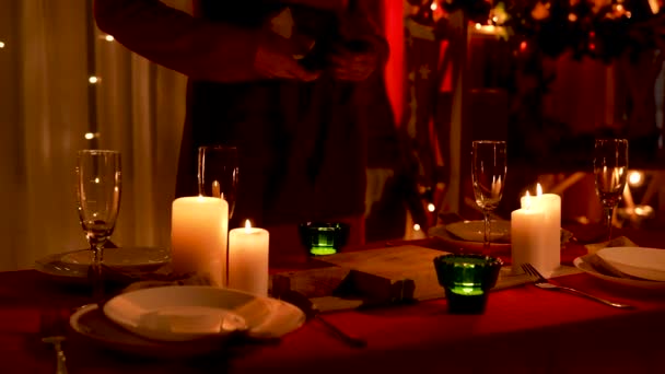 Femme essuie verres à champagne tout en se tenant près de la table festive avec des bougies et des ustensiles brûlants disposés. Chambre est décorée pour la célébration de Noël ou du Nouvel An. Les mains en l'air. Mouvement lent. — Video