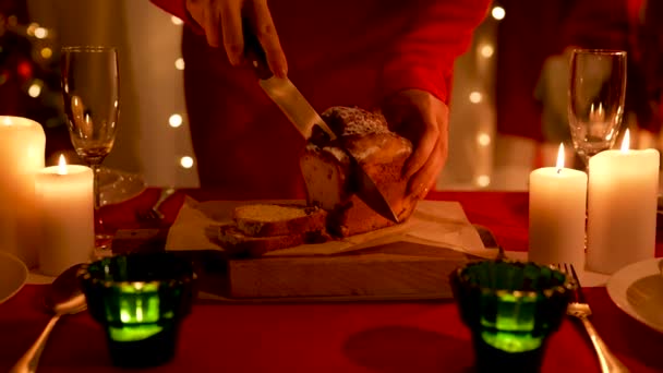 Vrouw snijdt traditionele zelfgemaakte cupcake op feestelijke tafel met borden en champagne glazen geregeld. Thuiskamer, ingericht voor het vieren van het nieuwe jaar of Kerstmis. Weinig licht. Sluit maar af. Langzame beweging. — Stockvideo