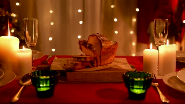 Κομμένο σπιτικό κεκάκι στο τραπέζι των διακοπών. Κάψιμο κεριών, πιάτα και ποτήρια σαμπάνιας κανονισμένα. Σπίτι άνετο δωμάτιο, διακοσμημένο για την Πρωτοχρονιά ή γιορτές των Χριστουγέννων. Χαμηλό φως. Κλείσε. Αργή κίνηση. — Αρχείο Βίντεο