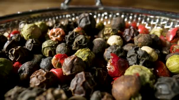 Geurige pittige zaden van droge pepers erwten close-up. Roze, zwarte en witte peperkorrels vallen op gekleurde stapel paprika 's mix. Specerijen voor het koken van kruidig voedsel. Vallende zaden van bittere erwten in slow motion. — Stockvideo