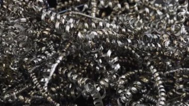 Metal talaşları, bükülmüş çelik renkli alüminyum spiraller. Çelik hurda malzemeleri geri dönüşüm. Torna tezgahındaki metal parçaları makineledikten sonra alüminyum çip atığı. Yakın çekim bükülmüş spiral çelik talaşı. Yavaş çekim.