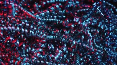 Parlak metal talaşları kırmızı ve mavi neon ışıklarla aydınlatılıyor. Bükülmüş çelik ya da alüminyum spiraller. Gümüş renkli metalin keskin spirallerinin makro görüntüsü. Parlak gümüş bukleler. Kapatın. Yavaş çekim.