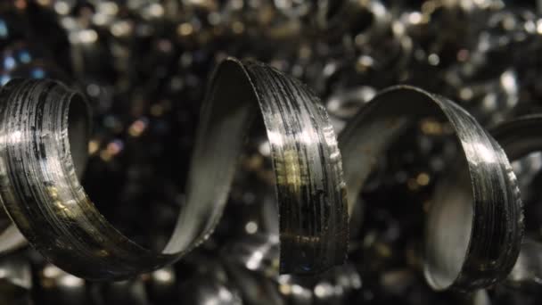 Gekrulde metalen spaanders na het uiteinde frezen. Macro shot van scherpe spiralen van zilverkleurig metaal. Afval van aluminiumkrullen. Camera pannen in stapel afval metalen krullen in slow motion. Sluiten.. — Stockvideo