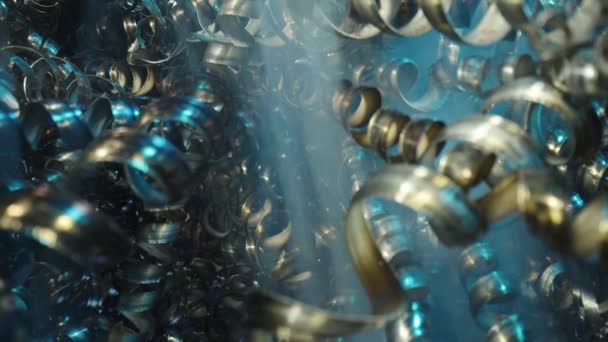 Camera pans along shiny metal shavings illuminated by blue neon lights. Twisted steel, aluminum spirals. Macro shot of sharp spirals of silver colored metal. Industrial waste. Close up. Slow motion. — Stock Video