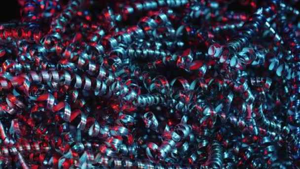 Shiny metal shavings illuminated by red and blue neon lights. Twisted steel or aluminum spirals. Macro shot of sharp spirals of silver colored metal. Shiny silver curls. Close up. Slow motion. — Stock Video