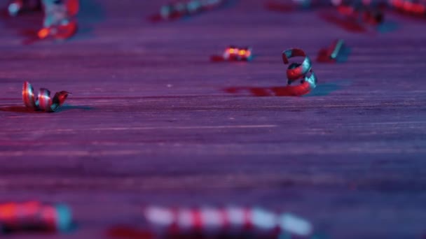 Las virutas espirales de metal brillante, iluminadas por la luz azul y roja, caen sobre una mesa de madera. Residuos de virutas metálicas en la industria del metal. Residuos industriales, rizos plateados. Cerca de virutas de acero en espiral. Movimiento lento. — Vídeos de Stock