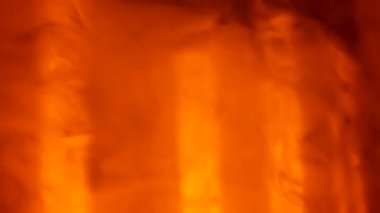 Cloud of smoke hovers and moves against background of dark empty studio in the rays of yellow red lighting stage lights. Colorful lighting effects on smoky dark nightclub stage. Close up. Slow motion.