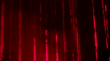 Red laser light beams on a dark smoky background. Colorful laser lights and smoke on party. Professional color lighting and sound show effects. Background of concert lights. Close up. Slow motion.