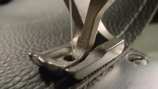 Macro shot of sewing machine needle with thread and presser foot tailoring leather piece during sewing process in handmade workshop. Slow motion of production operation. Sewing equipment close up. — Stockvideo