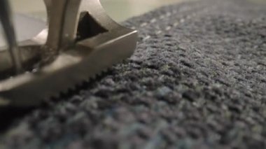 Gri yün kumaşı dikiş makinesiyle dikerken ayak ve iğne hareketleri. Dikiş makinesinin gümüş ütülü ayağı kumaşı bastırır ve iğneyle diker. Kapatın. Yavaş çekim.