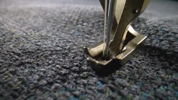 Presser foot of the sewing machine presses gray woolen fabric and stitches it with a needle. Notched rail advances the fabric while the sewing machine stitches it. Tailor craft. Slow motion. Close up. — Vídeo de Stock