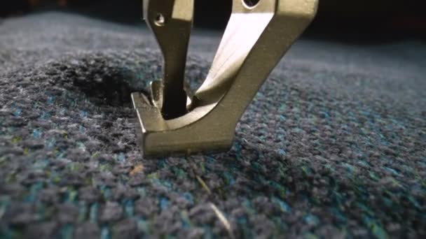 Presser foot of the sewing machine presses gray woolen fabric and stitches it with a needle. Notched rail advances the fabric while the sewing machine stitches it. Tailor craft. Slow motion. Close up. — Stockvideo