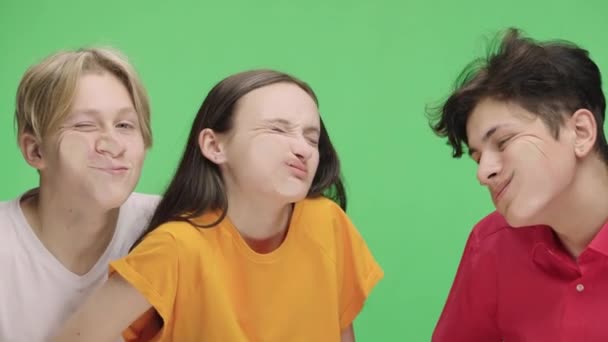 Group of young people imitate huddle in public transport, indignantly press their faces against glass. Girl and two guys are posing in studio against background of green screen. Close up. Slow motion. — Stockvideo