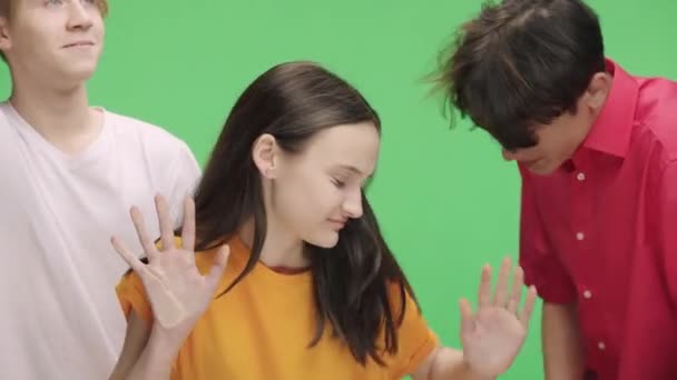 Een groep jongeren imiteert zich in het openbaar vervoer, drukt verontwaardigd hun gezicht tegen glas. Meisje en twee jongens poseren in de studio tegen de achtergrond van groen scherm. Sluit maar af. Langzame beweging. — Stockvideo