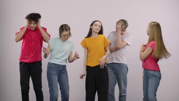 A group of cute young people looking at the camera and having fun dancing and having fun. Two guys and three girls models posing on a white background in the studio. Close up. Slow motion. — Stockvideo