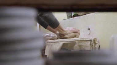 Çömlekçi erkek elleri yoğurur ve yumuşak, ıslak bir beyaz kil parçası oluşturur. El yapımı çömlek yapmak için kil malzemesi hazırlıyorum. Çömlekçilik kapanış aşamasında. Ağır çekimde kil yontuyorum..