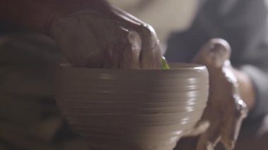Bir çömlekçi yumuşak killeri ıslak ellerle şekillendirir, el yapımı seramik yaratıcı demlik yaratır, çömlekçi çarkında döner. Çamur şekillendirme ve heykel yapma, atölyede el yaratıcılığını kapatma. Yavaş çekim.