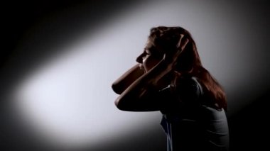 Heyecanlı genç bir kızın korku içinde bağırışının yan görüntüsü. Karanlık stüdyoda ön ışığı sahnelenmiş bir kız model. Kapatın. Yavaş çekim.