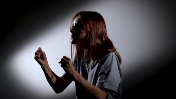 Silueta vista lateral de una joven excitada buscando en algún lugar con emoción esperando el resultado. Modelo de niña posando en estudio oscuro con luz frontal puesta en escena. De cerca. Movimiento lento. — Vídeo de stock