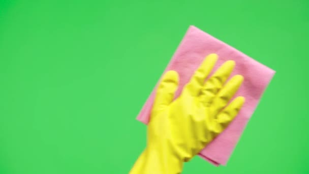 Frauenhand in gelben Gummihandschuhen wischt Fensterglas mit trockenem Lappen vor dem Hintergrund des grünen Bildschirmschlüssels ab. Hausfrau erledigt Hausarbeit. Reinigung von transparentem, glänzendem Glas vom Staub. Nahaufnahme. — Stockvideo