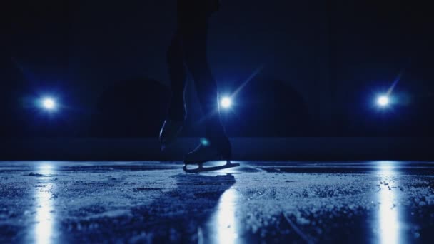 Pemain seluncur wanita muda menampilkan koreografi seluncur tunggal di arena es melawan cahaya biru lembut. Kaki skater artistik, berlatih meluncur dan rotasi di atas es. Gerakan lambat. Tutup.. — Stok Video