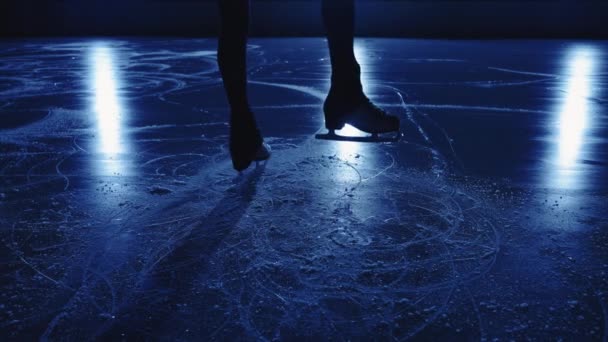 Gambe di atleta pattinatore che eseguono elementi di una coreografia femminile sola su ghiaccio di stadio. Giovane donna si prepara per le prestazioni praticando le sue abilità di scorrimento e filatura. Chiudi, rallenta.. — Video Stock
