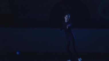 Profesyonel artistik patinajcı buz arenasında mavi ışıkta kayar ve döner. Buz gösterisinin repertuarını uygulayan genç bir kadın. Sanatsal spor, zarafet, hassasiyet ve mükemmellik. Yavaş çekim.
