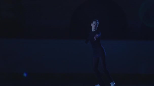 Professionele kunstschaatser dia 's en spins op het ijs arena in stralen van blauw licht. Jonge vrouw die repertoire oefent van een ijsshow. Artistieke sport, gratie, precisie en perfectie. Langzame beweging. — Stockvideo