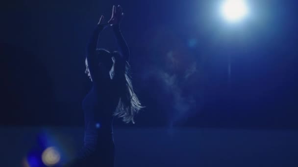 Műkorcsolya művész csúszik és forog a jég arénában a kék fény sugarai. Fiatal nő, aki egy jégshow repertoárját gyakorolja. Művészi sport, kecsesség, pontosság és tökéletesség. Lassú mozgás. Közelről.. — Stock videók