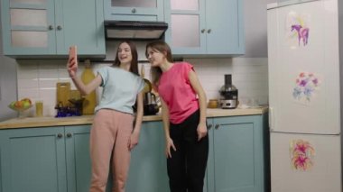 İki kız blogcu blogları ya da sosyal ağları için telefonla video içeriği kaydediyor. Medya hesabı veya vlog için mutfakta oluşturulan trend içeriği. Ağır çekim hazır, 4K 59.97 fps 'de..