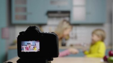 Kadın ve çocuğun dans edip komik videolar çektiği ekrana odaklan. Anne ve oğlu, sosyal medya yemek blogu için mutfakta hikayeler çekiyorlar. Blogcular. Ağır çekim hazır, 4K 59.97 fps 'de..
