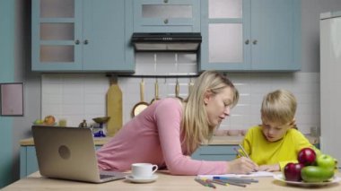 Albümde keçeli kalemle genç bir kadın ve bir oğlan çiziyor. Anne ve oğlu mutfakta. Aile blogcuları sosyal medya ve video blogu için hikayeler kaydediyor. Çevrimiçi vlog. Ağır çekim hazır, 4K 59.97 fps 'de..
