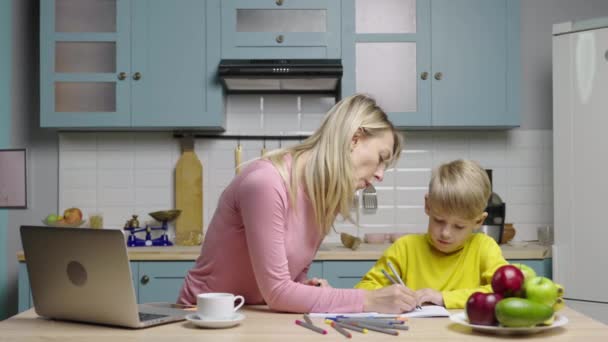 Jeune femme et un garçon dessinent avec des stylos feutre dans un album. Maman et fils dans la cuisine. Blogueurs familiaux filmant des histoires pour les médias sociaux et blog vidéo de la vie. Vlog en ligne. Ralenti prêt, 4K à 59.97fps. — Video